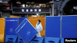 上海一名身穿防護服的工作人員站在封城使用的圍欄旁。 （2022年4月11日）