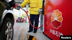 FILE - A gas station attendant pumps fuel into a customer's car at a PetroChina station in Nantong, Jiangsu province, China, March 28, 2018. China's demand for road and air transport fuels may have passed its peak, the International Energy Agency (IEA) said on Feb. 13, 2025.