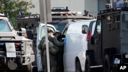 ສະມາຊິກຂອງທີມ SWAT ໄດ້ເຂົ້າໄປ ແລະກວດຄົ້ນເບິ່ງລົດຕູ້ສີຂາວໂດຍລະອຽດ ໃນເມືອງທໍແຣນສ໌, ລັດຄາລິຟໍເນຍ, ວັນທີ 22 ມັງກອນ 2023. ການໄລ່ລ້າມືປືນດັ່ງກ່າວເປັນເວລາຍາວນານຫຼາຍຊົ່ວໂມງ ໄດ້ເຮັດໃຫ້ເຈົ້າໜ້າທີ່ສາມາດລ້ອມຮອບ ແລະເຂົ້າໄປໃນລົດຄັນດັ່ງກ່າວໄດ້.