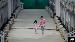 香港新冠病毒隔離設施中兩位隔離者走過一座座流動隔離間。