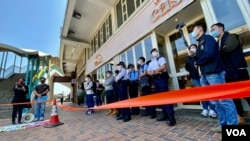 香港警方在距離北京駐港機構中聯辦超過100米的一間餐廳門外，拉起封鎖線設立”示威區”，禁止兩名社民連成員靠近中聯辦示威。(美國之音湯惠芸)