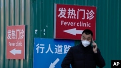 一名男子站在街頭打電話。他身後的紅色指示牌上寫著”發熱門診“。自從中國政府出人意料地突然放寬了封控措施之後，各地的感染人數不斷增加，使原本就貧乏的醫療資源面臨更沉重的壓力。