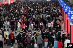 中国交通压力最大，一年一度的“春运”在如同海啸般蔓延的新冠感染爆发中拉开帷幕。广东深圳南站大厅内，旅客们人们带着口罩和行李，熙熙攘攘挤满大厅，等待买票和登车。本照片由新华社发布，美联社提供。