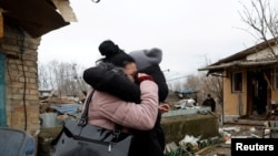 在基輔，一名當地居民在被俄羅斯導彈襲擊破壞的房屋與朋友擁抱。(2022年12月29日)
