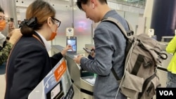 港鐵職員指導高鐵乘客使用西九龍總站入閘機的人面識別系統。(美國之音湯惠芸)