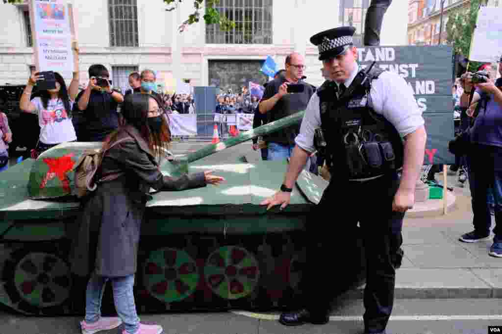 示威者把紙紮坦克擺在中國駐英大使館外並企圖移動，但被在場警察按下。（美國之音鄭樂捷）