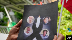 2022年7月26日，星期二，一名居住在泰國的緬甸人拿著被處決的政治犯的照片，他們在泰國曼谷的緬甸大使館外抗議。國際社會對緬甸處決四名政治犯感到憤怒。