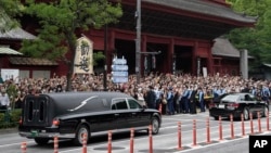 日本前首相安倍晉三的葬禮舉行後，運載安邦棺木的靈車離開寺廟，日本民眾路旁送行。（2022年7月12日）