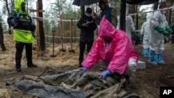 一名專家在烏克蘭伊久姆對一名被發現的平民屍體進行檢查（2022年9月24日）