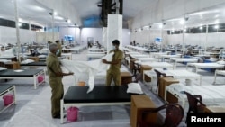 印度工人在孟買新近為新冠病毒感染者修建的隔離設施里為病人準備床鋪。 （2020年6月22日）