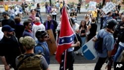 維吉尼亞夏洛特維爾市一名白人至上主義者手持南方邦聯旗從反示威人群中走過。 (2017年8月12日)