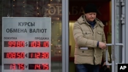 FILE - A man leaves a bank displaying currency exchange rates in Moscow, Dec. 20, 2024. 