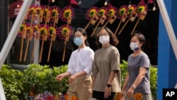 戴著口罩的行人走過北京街頭一個售賣傳統風車玩具的商舖。 （2022年9月13日）