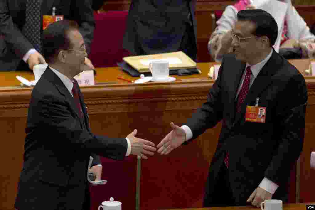 即将离任的中国总理温家宝2013年3月5日在第十二届人大开幕式上和他预计的继任者副总理李克强握手。