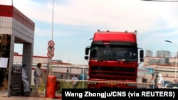 中國發現非洲豬瘟後，河南省鄭州肉類加工企業雙匯集團大門處可以看到身著防護服的工人。（2018年8月17日）