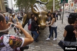 中國遊客在紐約華爾街的銅牛前合影。 （2015年8月24日）