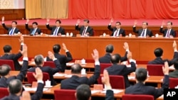 2021年11月11日，中共第19届中央委员会第六次全体会议上，政治局常委们举手表决。从左向右依次是韩正、王沪宁、栗战书、习近平、李克强、汪洋和赵乐际。照片由新华社发表，美联社提供。