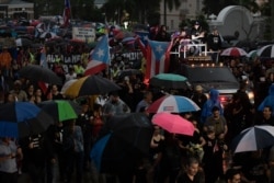 People take part in a protest organized by Puerto Rican singer Rene Perez of Calle 13 over emergency aid sitting unused in a warehouse amid ongoing earthquakes, in San Juan, Puerto Rico, Jan. 23, 2020. Protesters demanded Gov. Wanda Vazquez resign.