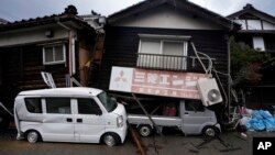 ​ລົດ​ຖືກ​ທັບ​ໂດຍ​ເຮືອນ​ທີ່​ຍຸບ​ລົງ​ໃນ​ເມືອງ ວາ​ຈິ​ມະ, ແຫຼມ ໂນ​ໂຕະ, ຍີ່​ປຸ່ນ, 7 ມັງ​ກອນ 2024.