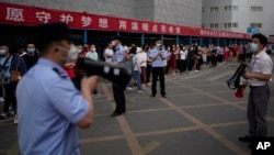 中国高考第一天，北京一处考场外警察和学校教师使用扩音器要求在外等候的考生家长遵守秩序。（2022月6月7日）