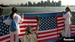 资料照：两名华人女子在纽约手举自由女神像与美国国旗的横幅。