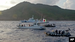 日本海上保安厅船只与一艘悬挂日本国旗的由日本活动人士驾驶的渔船在尖阁诸岛附近（中国称到钓鱼岛）。（资料照：2013年8月18日））