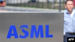资料照：一名员工走过世界最大半导体制造机器供应商、位于费尔德霍芬的荷兰阿斯麦公司（ASML）总部的标识。（2018 年4月17日）