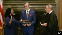 凯坦吉·布朗·杰克逊在美国最高法院首席大法官罗伯茨的主持和丈夫帕特里克·杰克逊医生的注视下宣誓就任大法官。（2022年6月30日）