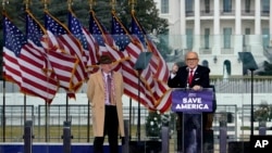 在衝擊國會大廈事件發生前舉行的一次集會上，查普曼大學法學教授伊士曼(左)站在正在發言的前紐約市長朱利亞尼旁邊。(2023年8月22日)