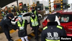 戴著面具的警察在武漢咸寧的高速繳費站檢查汽車裡是否載有偷運的野生動物。（2020年1月24日） 