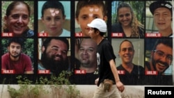 以色列特拉维夫一名男子走在10月7日哈马斯致命袭击中被绑架的人质海报前，下排左一为以色列裔美国人赫什·戈德堡-波林。(路透社：2024年9月1日)
