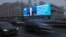 Автомобили проносятся по Кутузовскому проспекту - правительственной магистрали Москвы - мимо электронного экрана, на котором - изображение Владимира Путина и цитата из его пресс-конференции. REUTERS/Шамиль Жуматов/19 декабря 2024 года