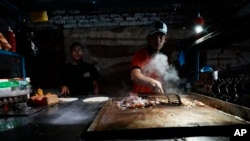 ຄົນ​ຂາຍ​ອາ​ຫານ​ຕາມ​ຖະ​ໜົນ​ກ​ະ​ກຽມ​ອາ​ຫານ​ດ້ວຍ​ໄຟ​ທີ່​ມາ​ຈາກ​ຈັກ​ປ້ຳ​ໄຟ​ຟ້າ, ເມືອງ ມານ​ຕາ, ເອ​ກົວ​ດໍ, 23 ກັ​ນ​ຍາ 2024.(AP Photo/Dolores Ochoa)