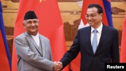 中国国务院总理李克强与来访的尼泊尔总理奥利在人民大会堂签字仪式上握手(2018年6月21日路透社)