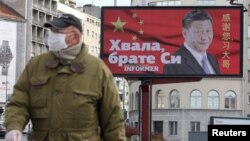 塞爾維亞一名戴著口罩的男子走過貝爾格萊德街頭樹立的感謝中國領導人習近平的廣告牌旁。 （2020年4月1日）