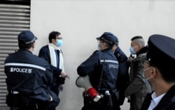 大批警员包围民阵副召集人叶锦龙，一度指控民阵2021元旦日车巡活动违反限聚令， 最后登记叶锦龙身分证资料后放行，没有发出任何告票 (美国之音/汤惠芸）