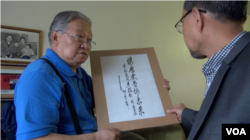 李振盛展示任仲夷题词“让历史告诉未来” (美国之音章真拍摄)