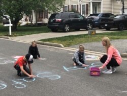 Family members write chalk messages to their neighbors as they stay at home during the coronavirus outbreak, in Glen Allen, Va., March 26, 2020.