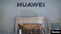 人們走過北京街頭的華為專賣店。（2021年6月3日）