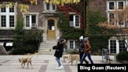 資料照片：新冠疫情期間，人們攜犬走過威斯康星大學麥迪遜分校的校園。 (2020年10月19日)
