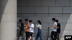 北京写字楼前年轻人边走路边看手机。