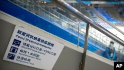 在北京一座室内体育馆的冰球场，一名工作人员站在写有如果防止感染新冠病毒措施的标牌附近。（资料照）