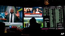 The first public impeachment hearing of President Donald Trump plays on a screen at the Superbook sports book inside the Westgate casino-hotel Wednesday, Nov. 13, 2019, in Las Vegas. (AP Photo/John…