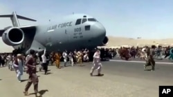 美國空軍C-7運輸機在喀布爾國際機場起飛時上百人在跑道上跟隨奔跑。 （2021年8月16日）
