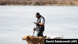 ແຟ້ມພາບ - ຊາຍຄົນນຶ່ງກຳລັງຈູງໝາຍ່າງຫຼິ້ນ ຂະນະທີ່ເບິ່ງໂທລະສັບມືຖືໄປພ້ອມ ທີ່ສວນວໍຊິງຕັນ ພາກຣ໌ ນະຄອນເດັນເວີ ລັດໂຄໂຣລາໂດ ເມື່ອວັນທີ 21 ກຸມພາ 2023. (AP Photo/David Zalubowski, File)