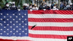 在911事件19週年紀念儀式中，當美國國歌響起時一面美國國旗在國家911紀念館前展開。 （2020年9月11日）