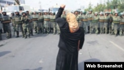 一名新疆維吾爾婦女舉拳向一隊中國武警士兵表示抗議。 (照片來自世界維吾爾代表大會網站)