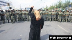 一名新疆維吾爾婦女舉拳向一隊中國武警士兵表示抗議。(照片來自世界維吾爾代表大會網站)