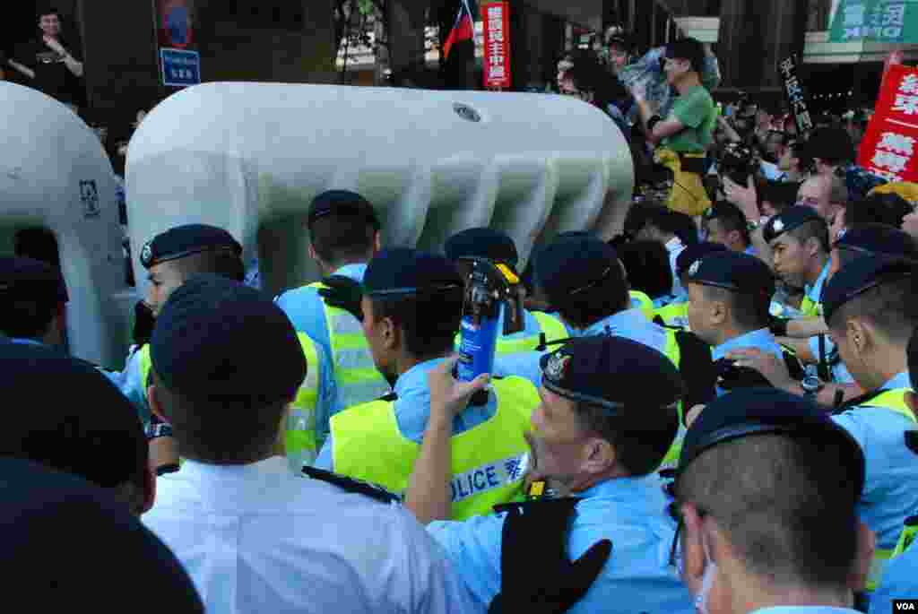 大批示威者不滿示威區範圍太小企圖推倒水馬陣防線，與香港警方發生衝突，有香港警員手持胡椒噴霧(藍色罐)