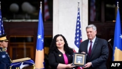 科索沃總統維約薩·奧斯馬尼（中）在頒獎典禮上將勳章交給美國大使菲利普·克斯內特。